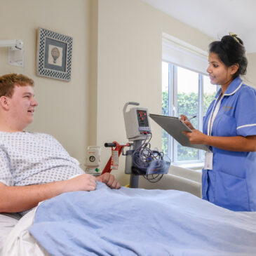 A nurse talks with a patient in their private room