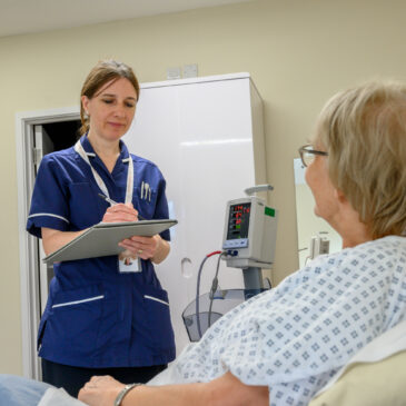 A nurse takes notes while speaking to a patient