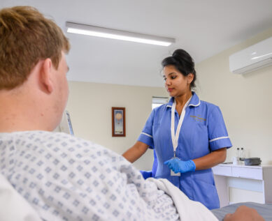 A nurse talks with a patient in their private room