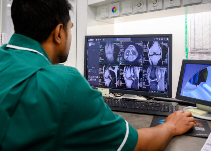 An MRI technician looks at scans on their computer